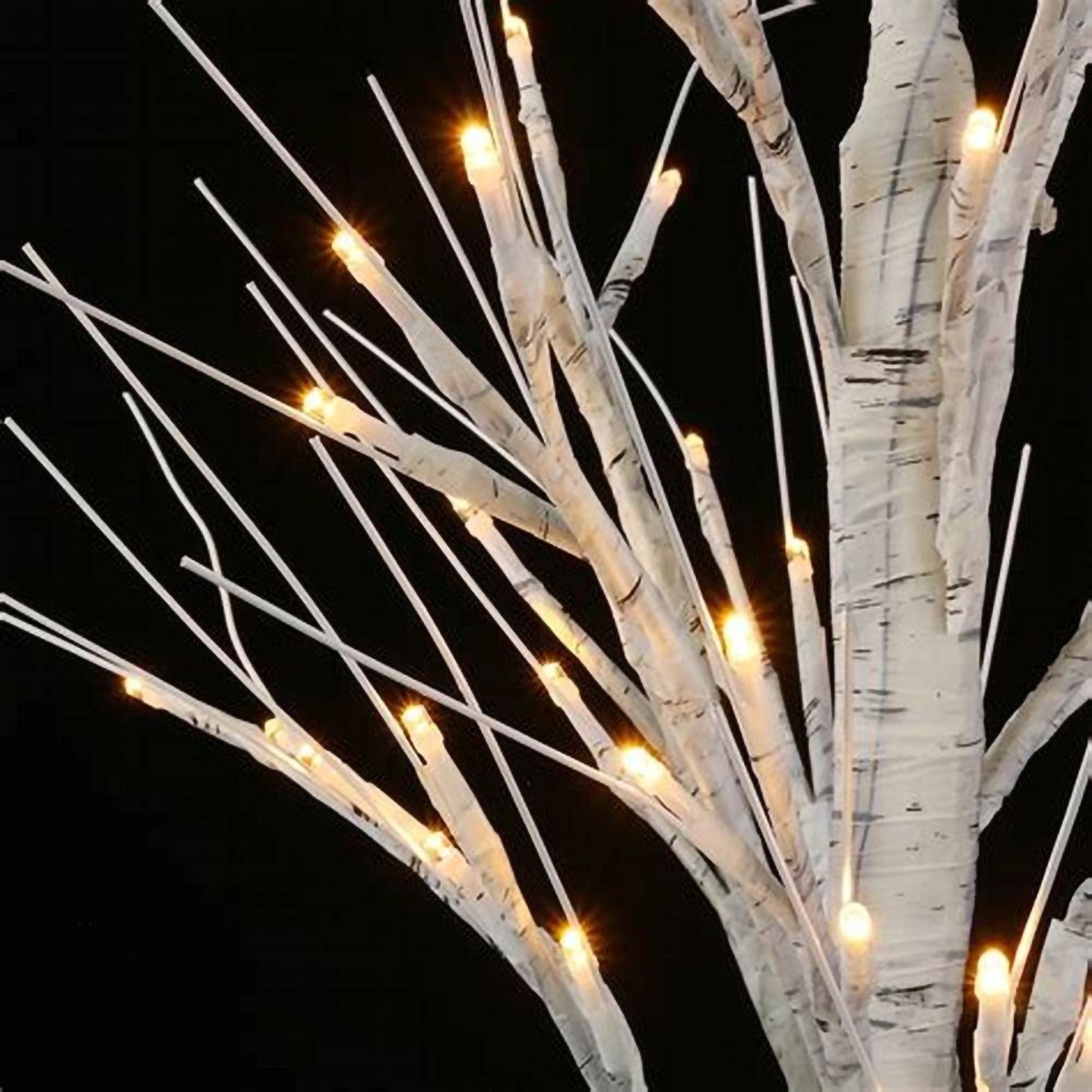 Zbliżenie na dekoracyjne drzewko LED, stylizowane na brzozę. Gałęzie drzewka są białe, z widoczną fakturą przypominającą korę brzozy, a wzdłuż nich umieszczone są małe, ciepłe diody LED, które emitują światło. Tło jest ciemne, co podkreśla oświetlenie gałęzi.